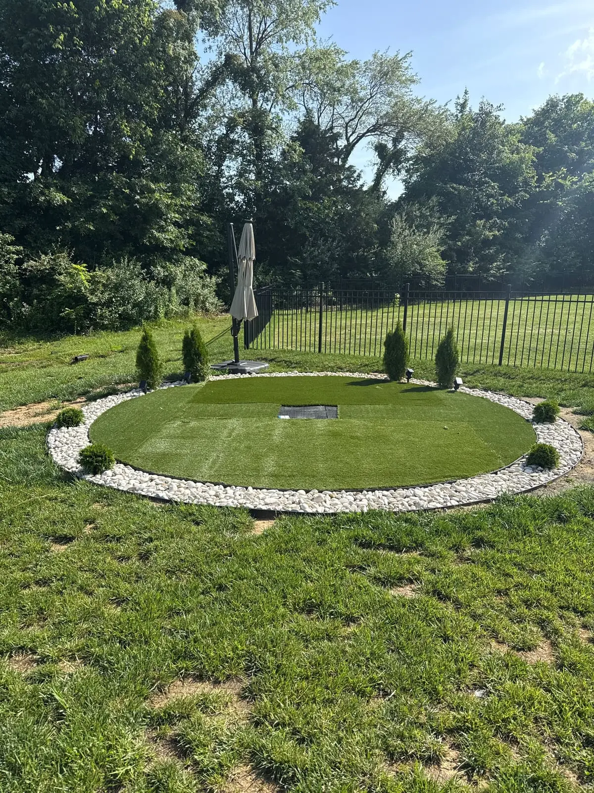 Backyard putting green with artificial turf and white stone border in Bloomington, IN