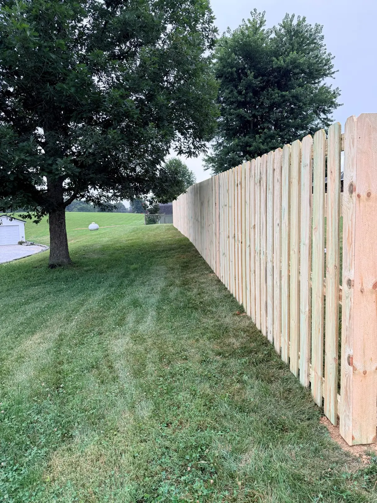 Shadowbox wood fence along a property line with open farmland view in Bloomington, IN