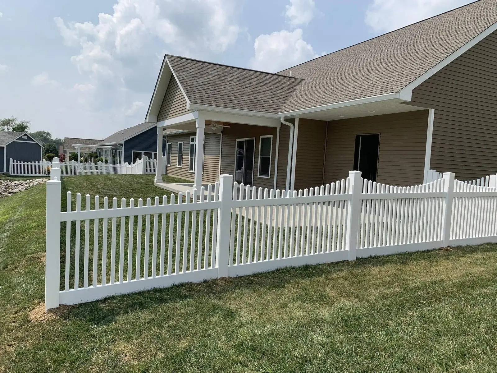 White vinyl scalloped picket fence installed in the front yard of a ranch home in Bloomington, IN