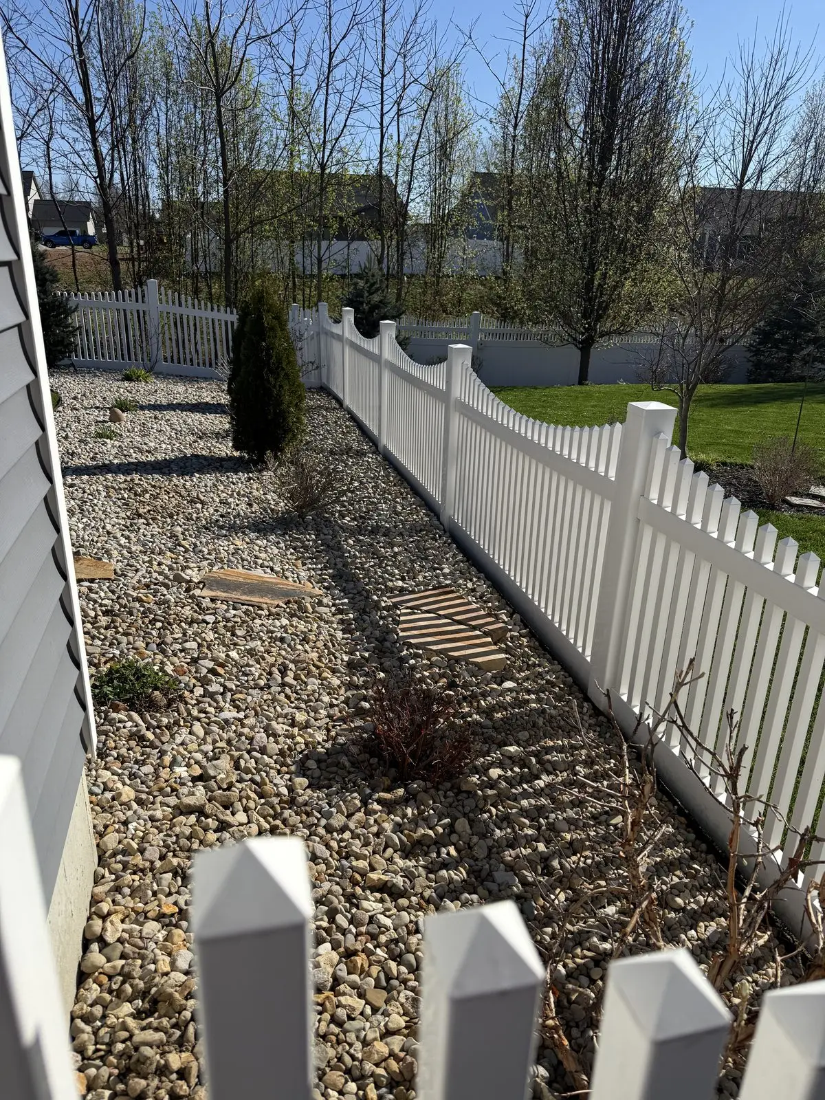 White vinyl picket fence with river rock landscaping in Bloomington, IN