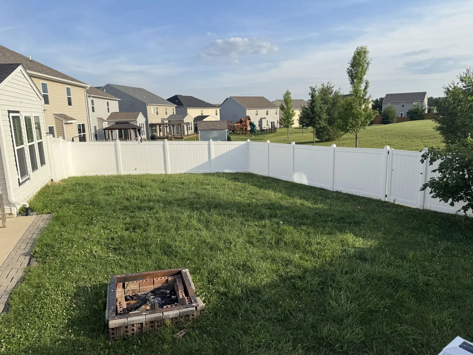 White vinyl privacy fence around a large backyard with fire pit in Bloomington, IN