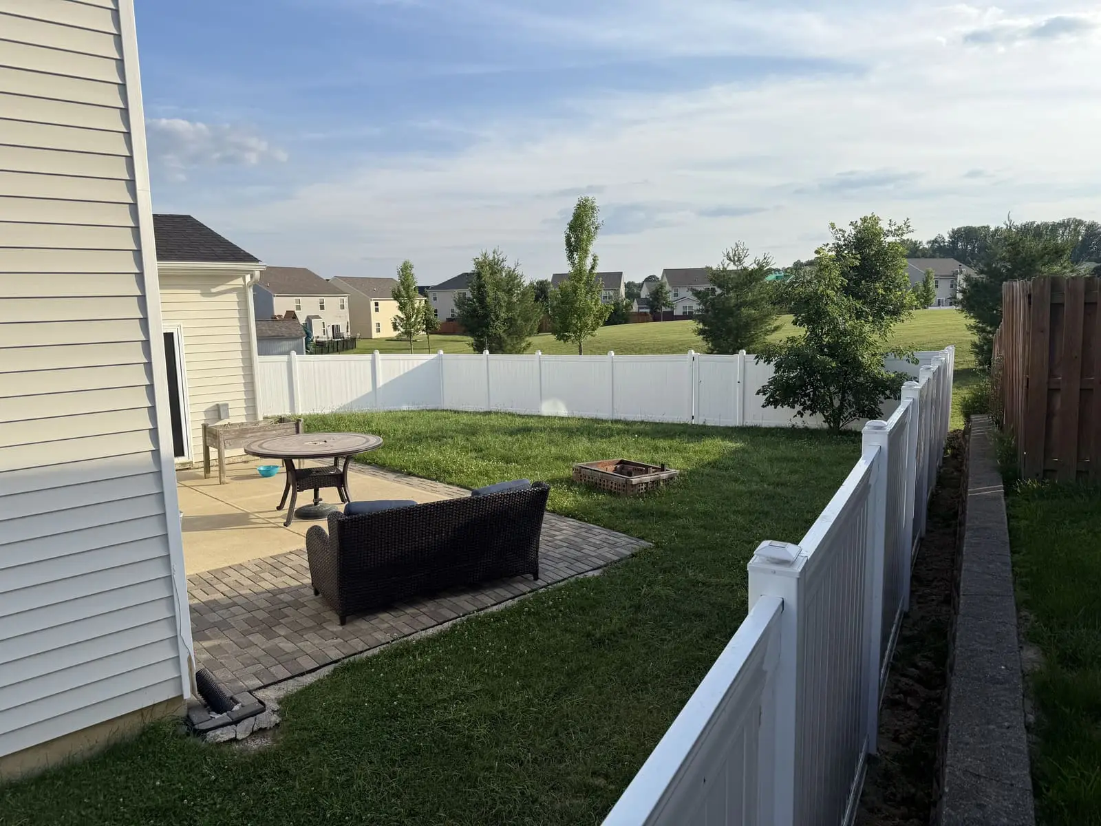 White vinyl privacy fence enclosing a backyard with paver patio in Bloomington, IN