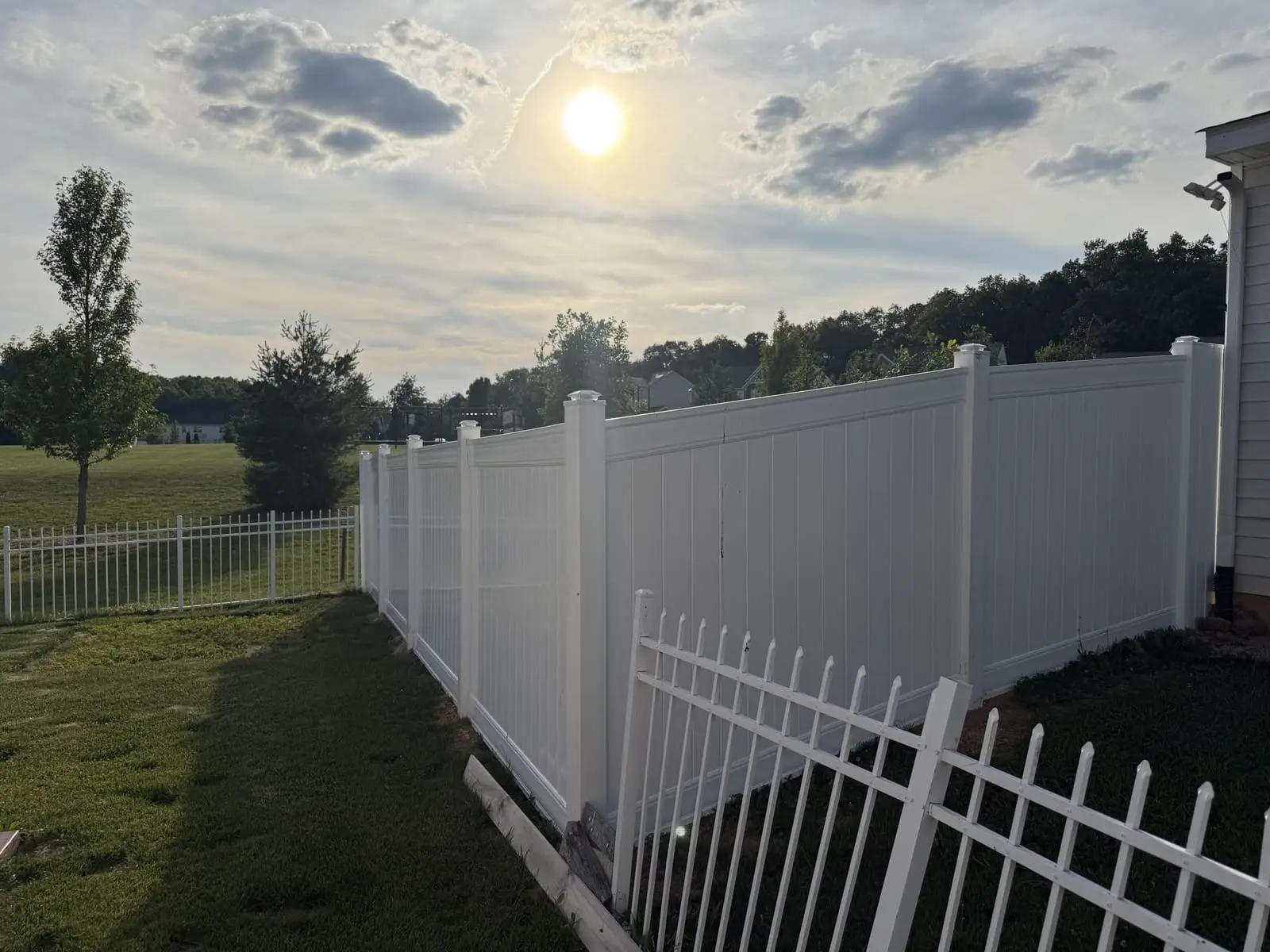 New white vinyl privacy fence installation at sunset in Bloomington, IN