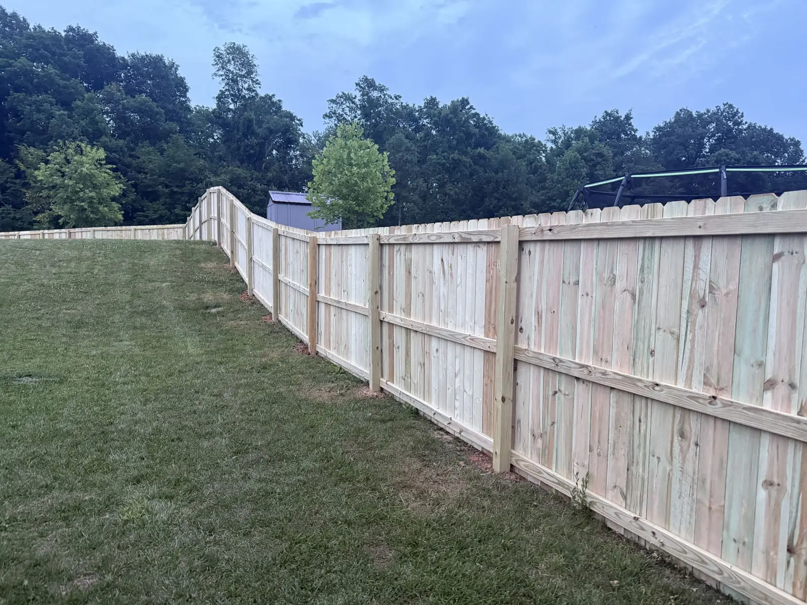 Wood privacy fence with back rails stepping up a hillside in Bloomington, IN