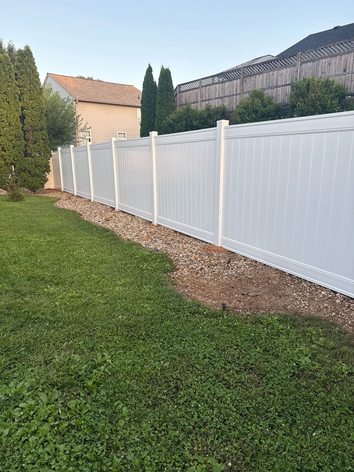 After: straight new white vinyl privacy fence along the same line in Bloomington, IN