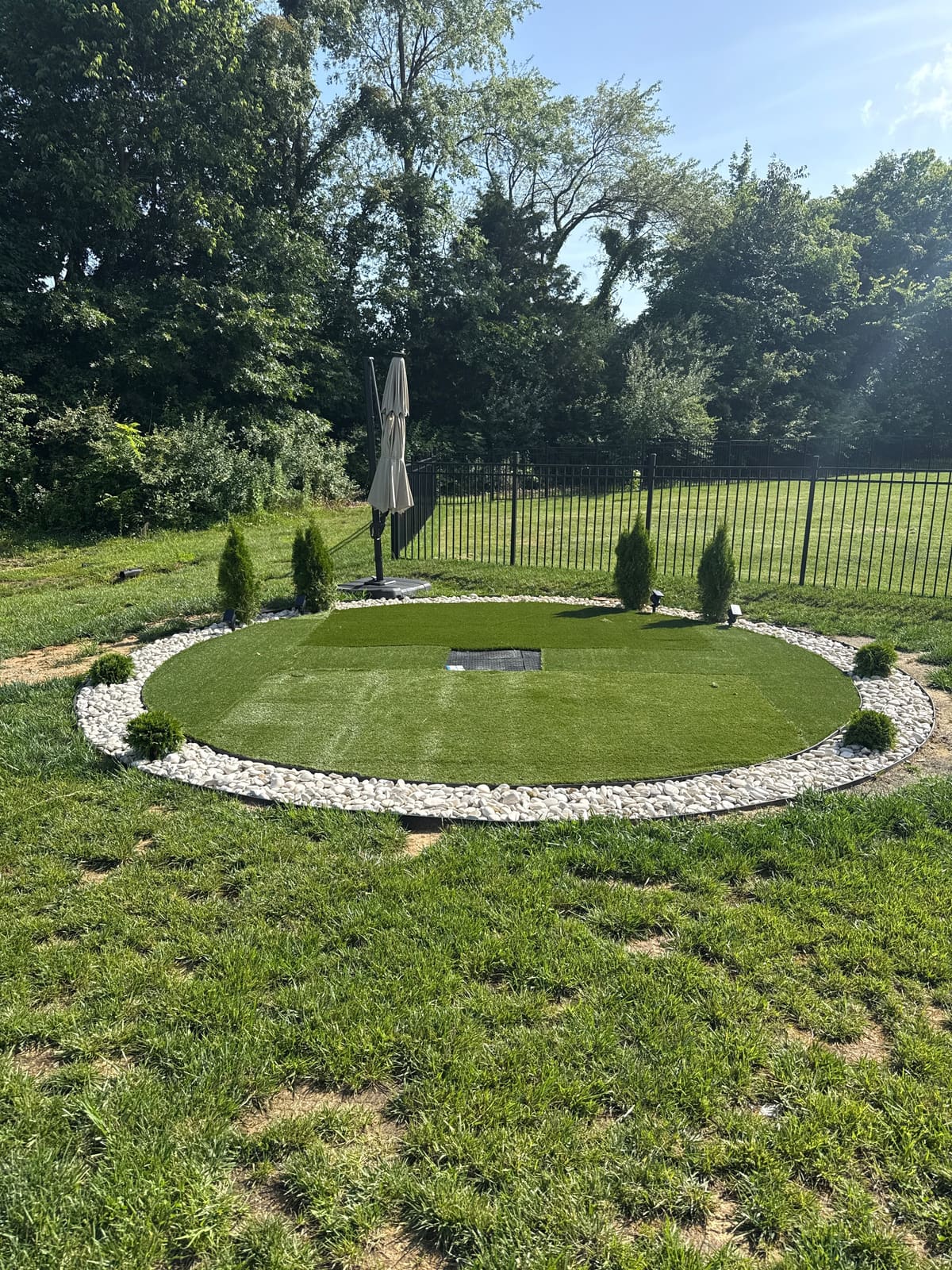 Backyard putting green with artificial turf and white stone border in Bloomington, IN