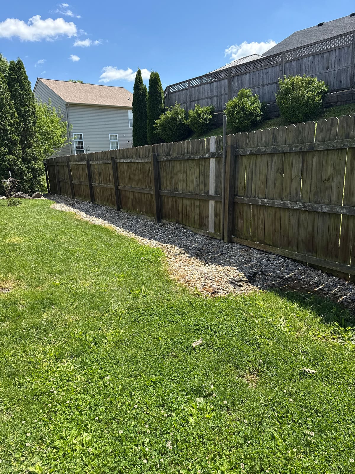Before: aging wood privacy fence leaning along a gravel drainage bed in Bloomington, IN