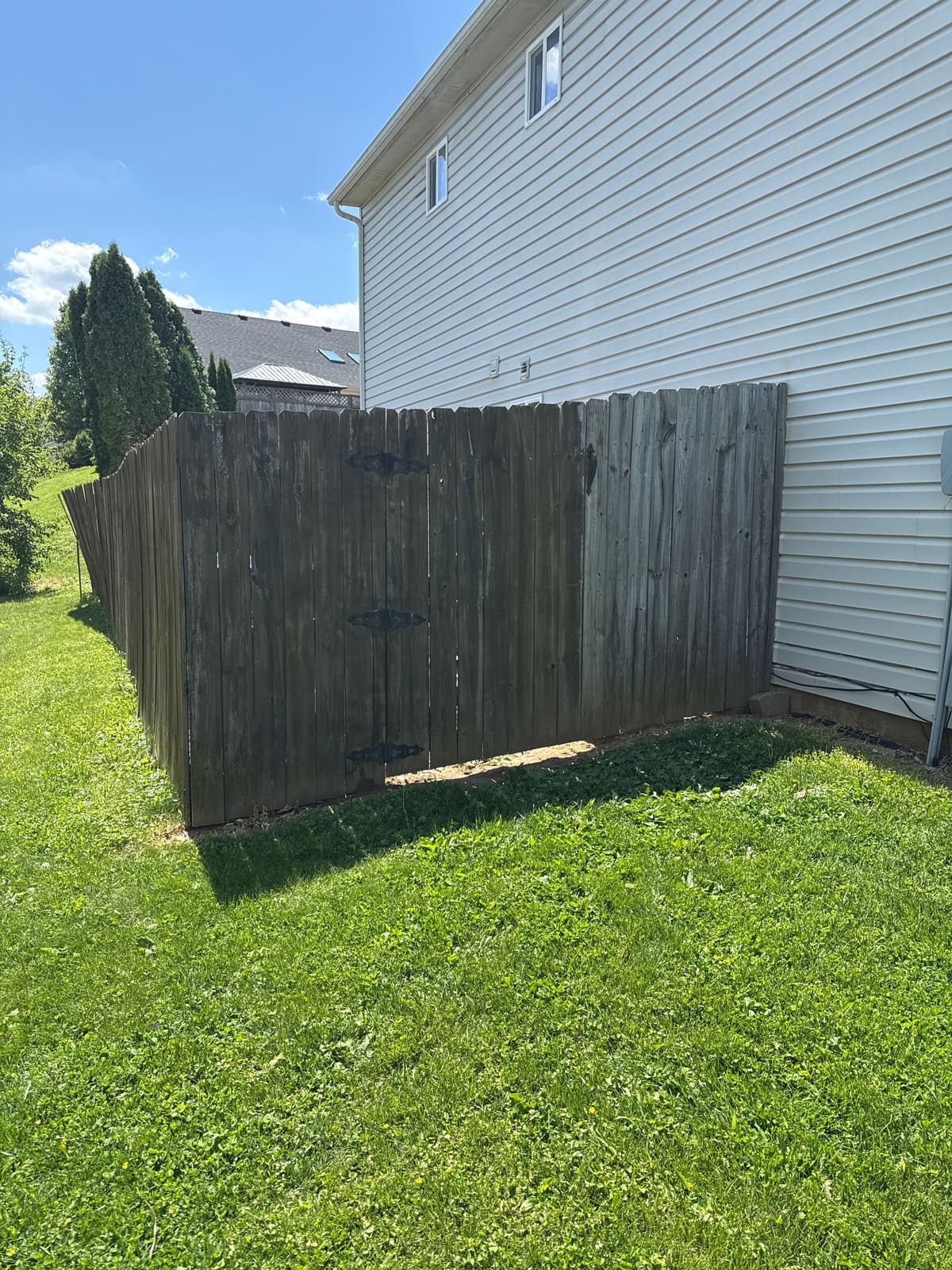 Before: weathered wood privacy fence and gate against a home in Bloomington, IN
