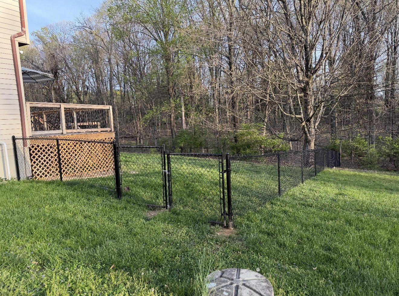 Black chain link fence installation along a backyard in Bloomington, IN