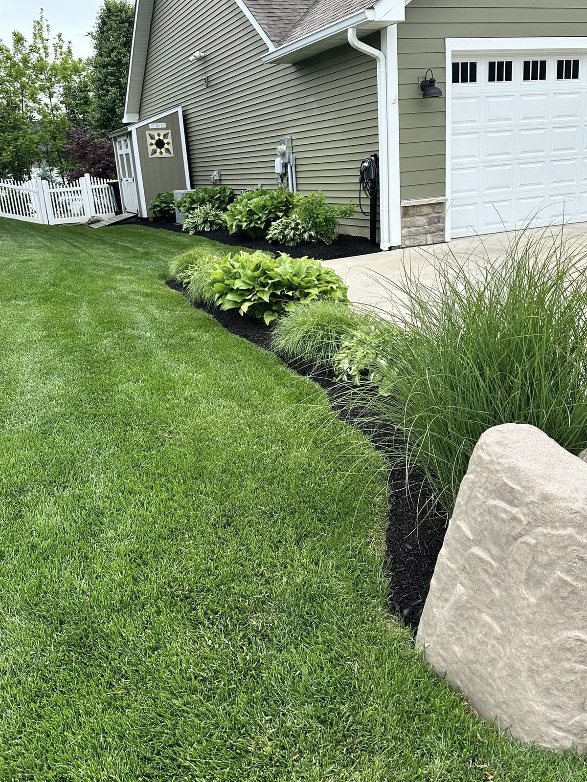 Mulch bed landscaping along a driveway in Bloomington, IN