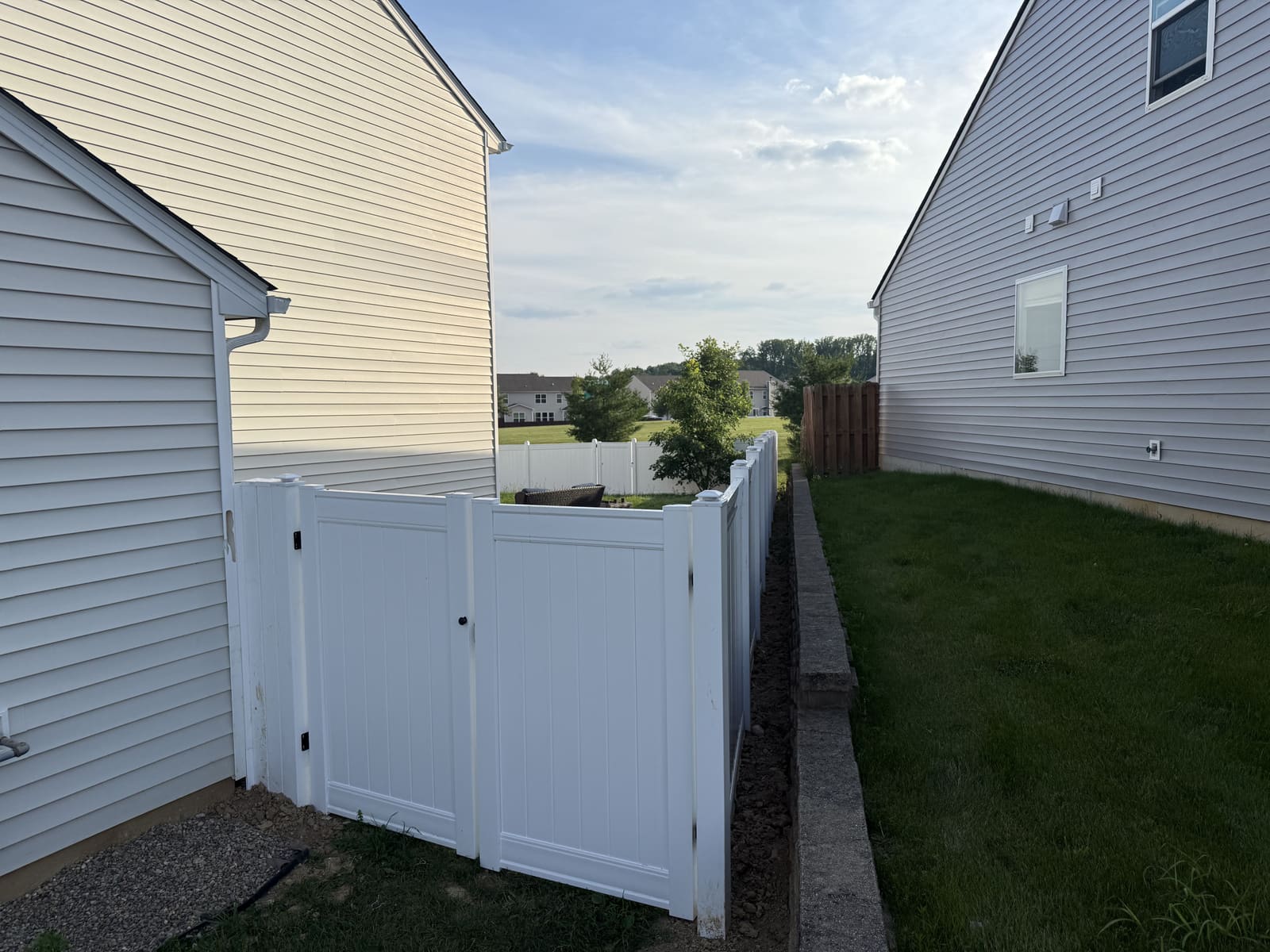 White vinyl fence and gate along a retaining wall between homes in Bloomington, IN