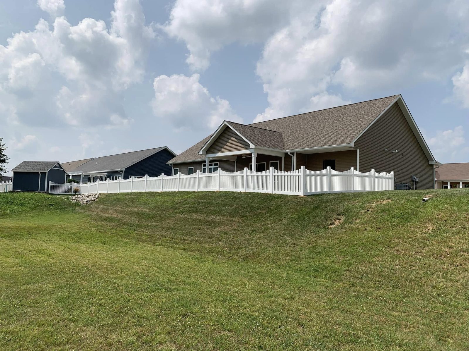 White vinyl picket fence installation wrapping a hillside home in Bloomington, IN