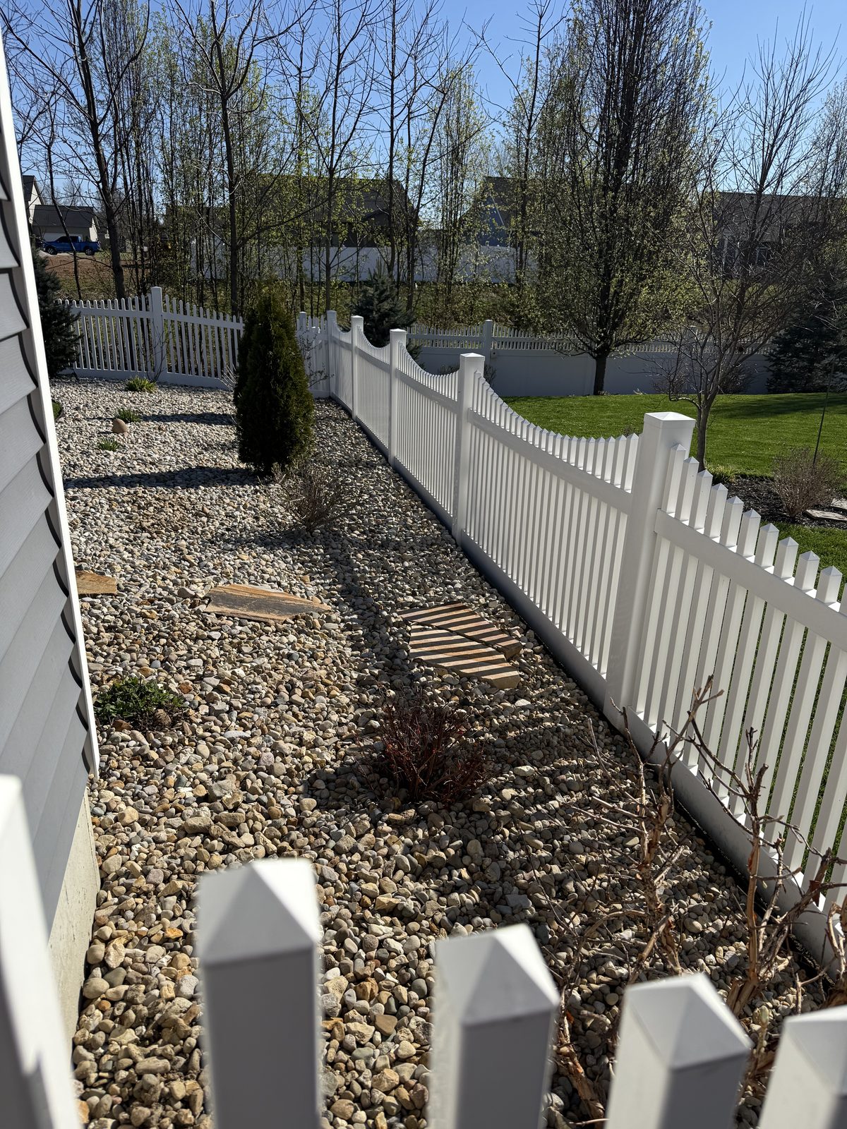 White vinyl picket fence with river rock landscaping in Bloomington, IN