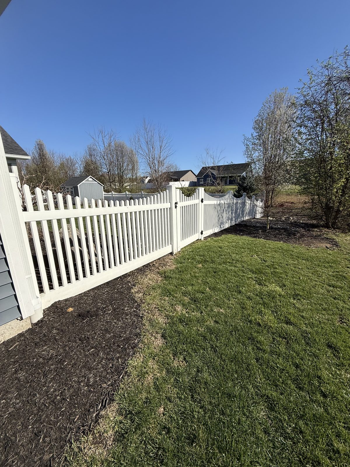 White vinyl scalloped picket fence enclosing a yard in Bloomington, IN