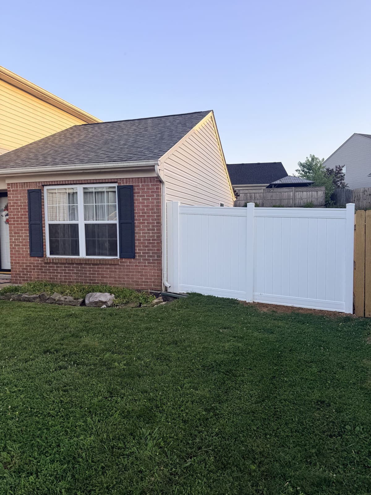 White vinyl privacy fence at the corner of a brick home in Bloomington, IN