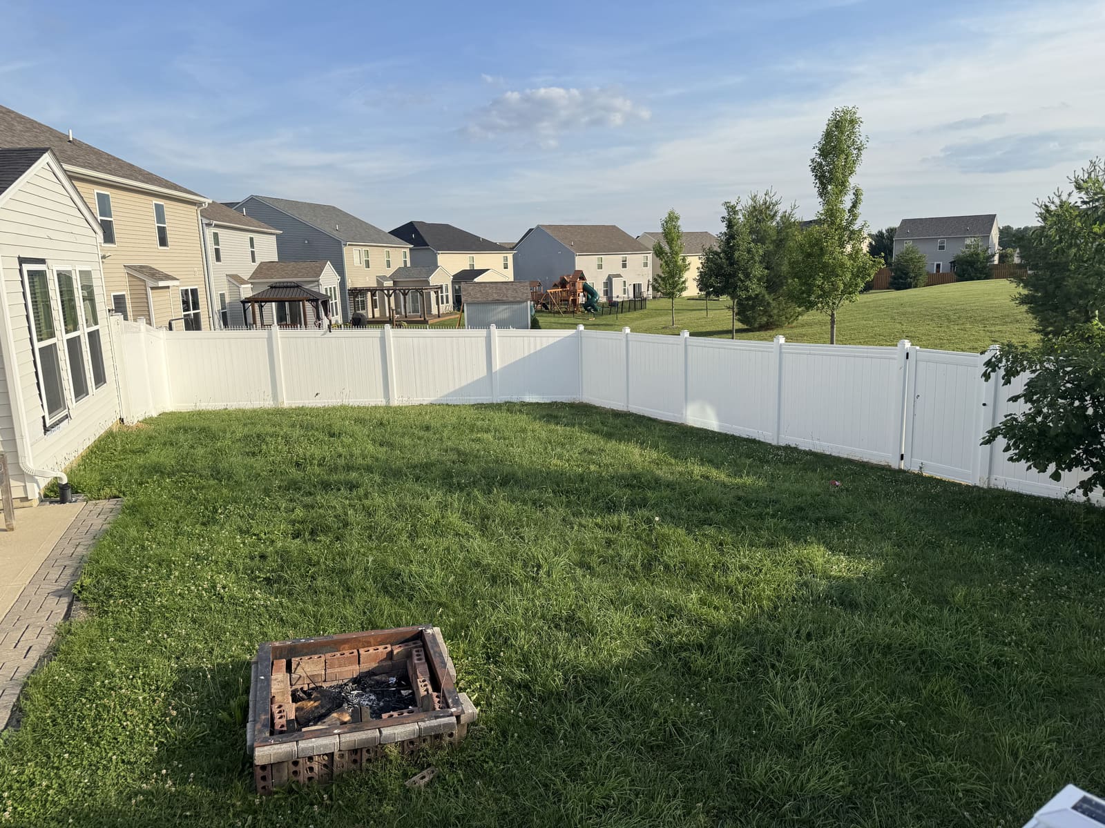White vinyl privacy fence around a large backyard with fire pit in Bloomington, IN