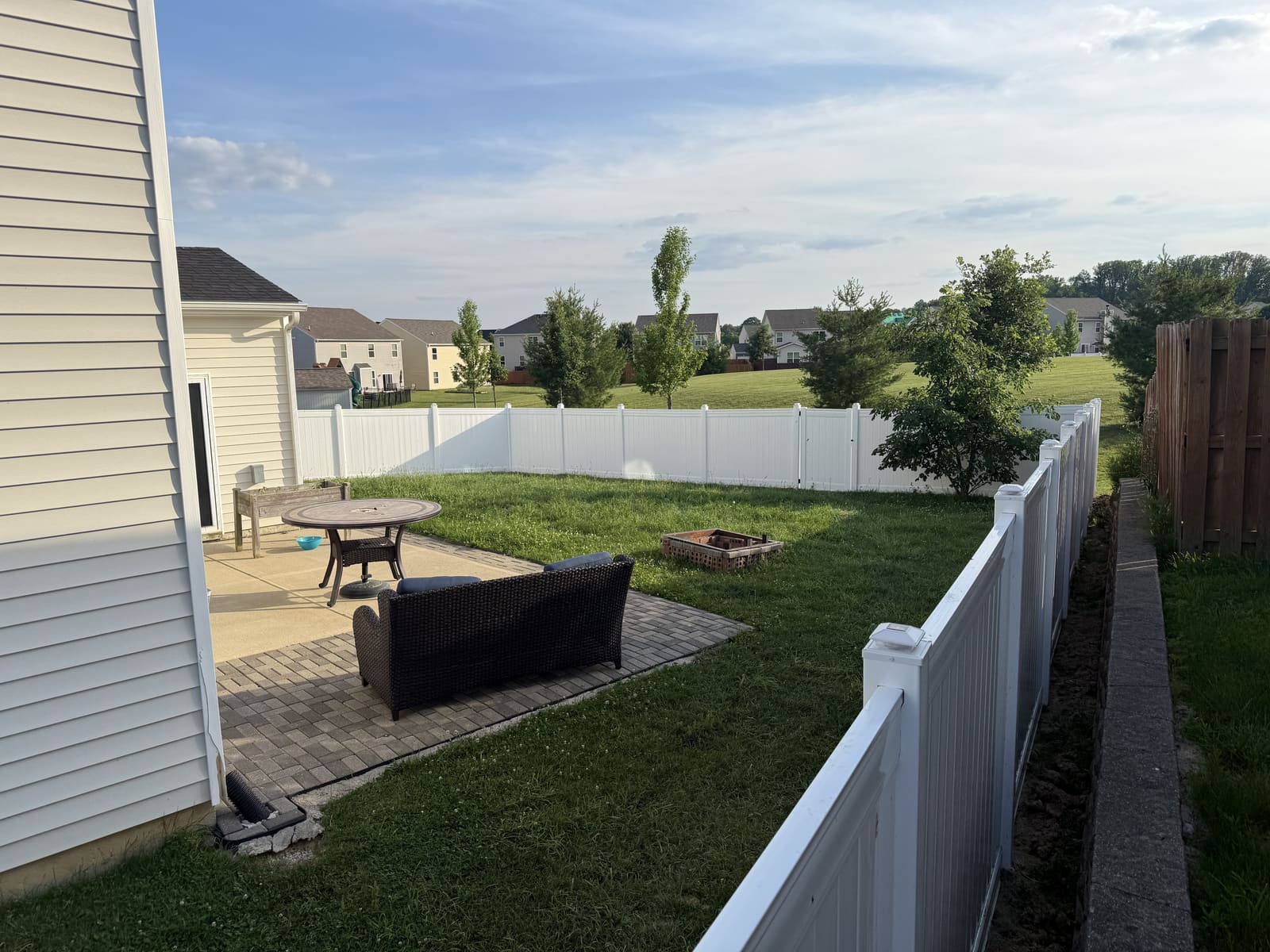 White vinyl privacy fence enclosing a backyard with paver patio in Bloomington, IN