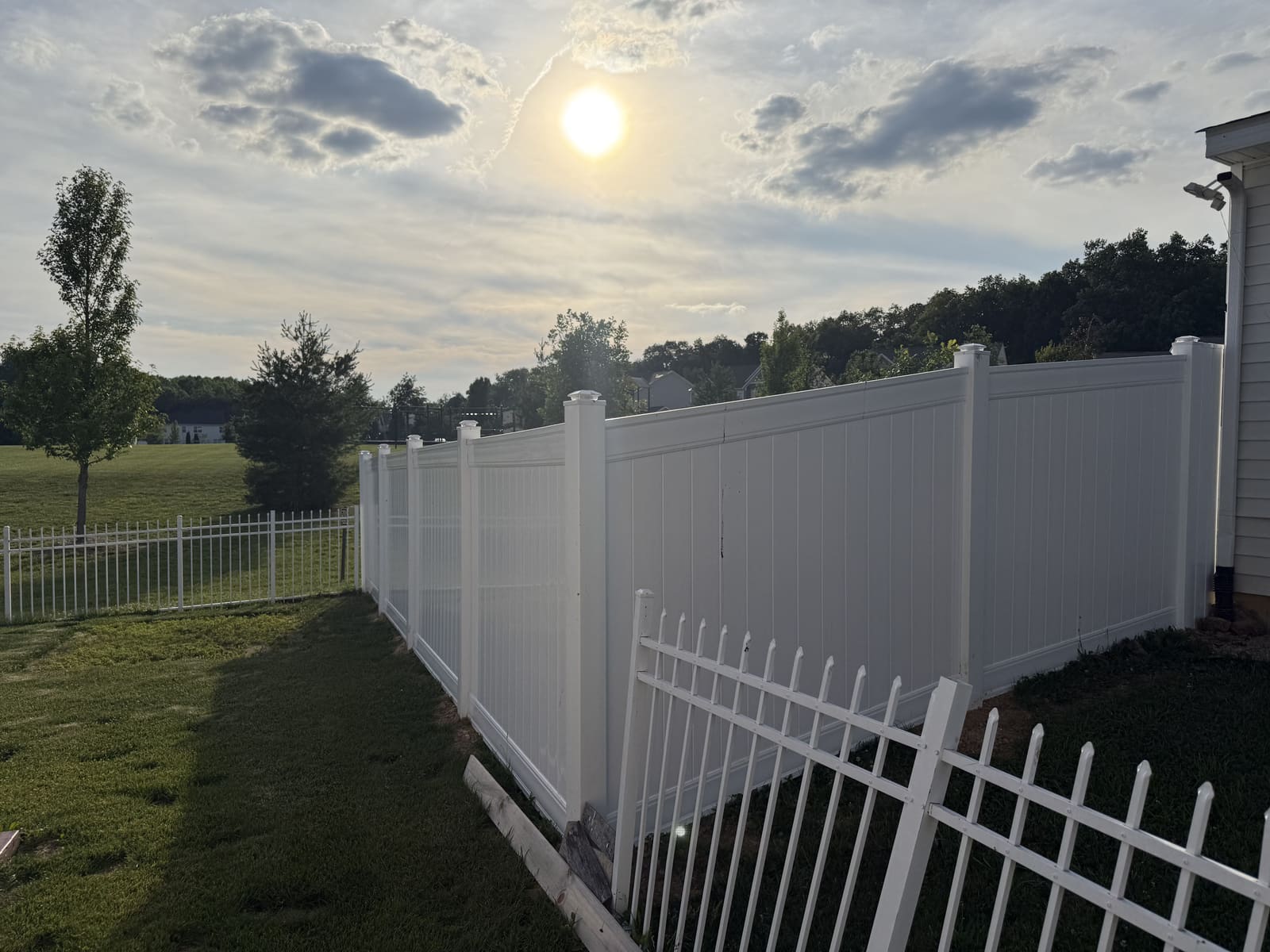 New white vinyl privacy fence installation at sunset in Bloomington, IN