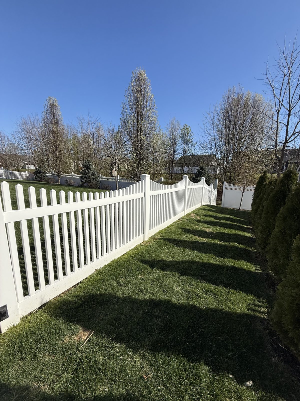 White vinyl scalloped picket fence in a backyard in Bloomington, IN