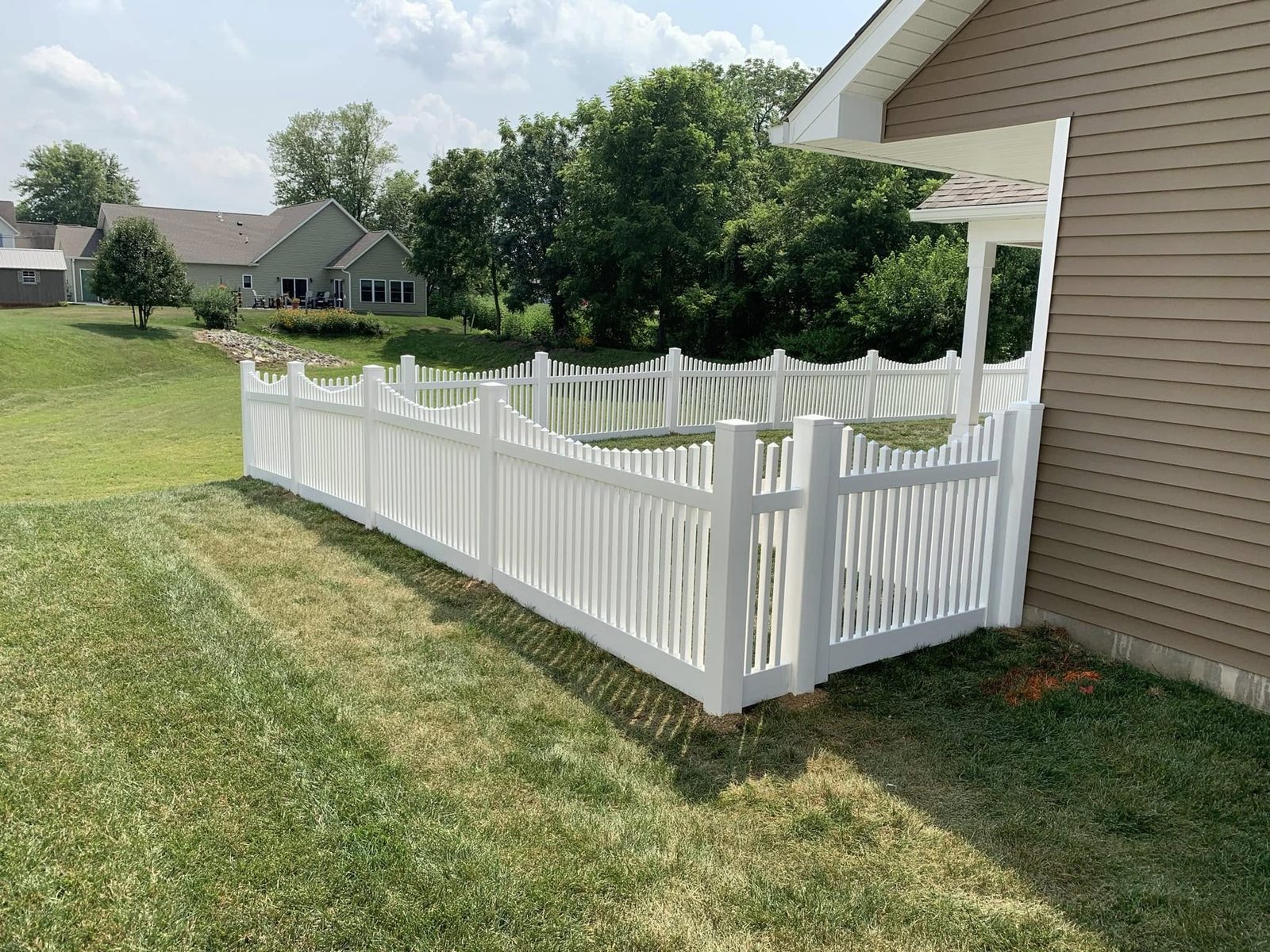 White vinyl scalloped picket fence along a side yard in Bloomington, IN
