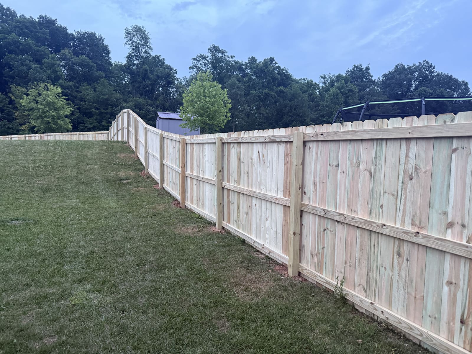 Wood privacy fence with back rails stepping up a hillside in Bloomington, IN